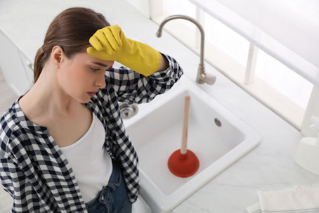woman sweating from working on kitchen sink